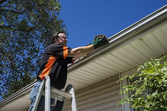 gutter repair specialist using ladder to access rooftop in Ardsley